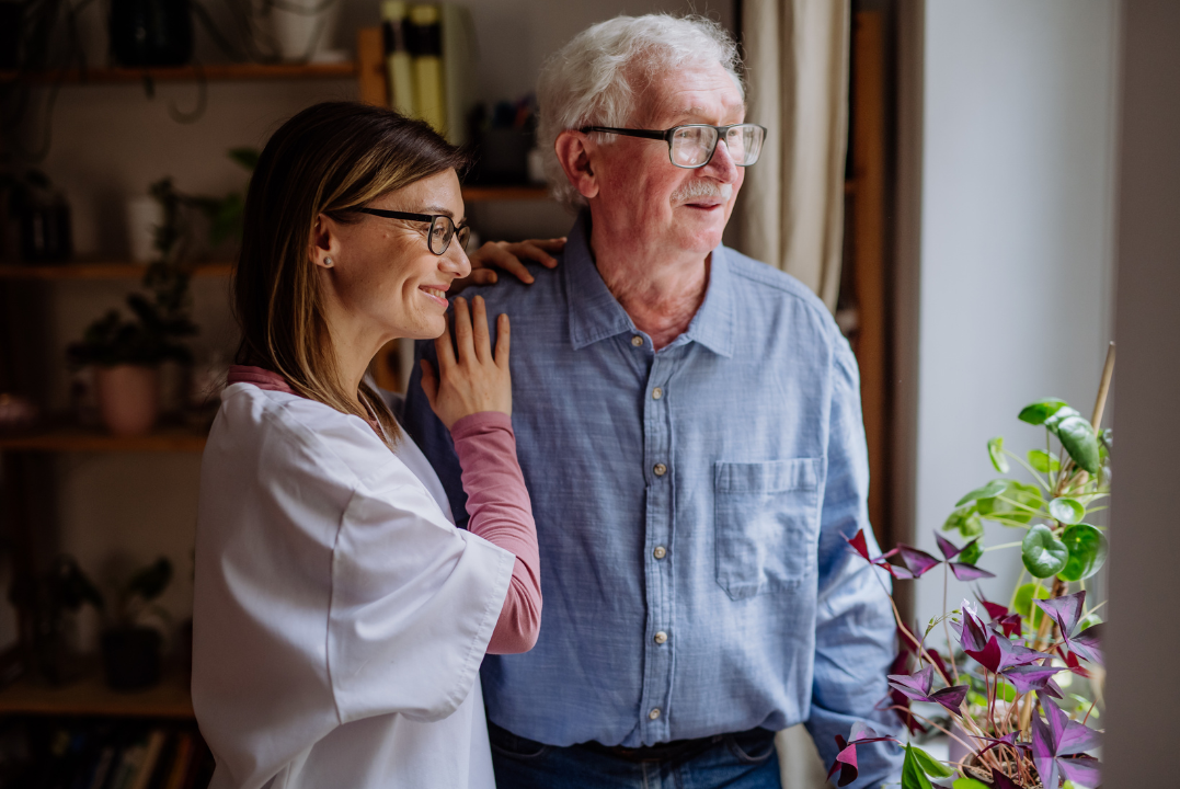 Man with Alzheimer's Looking Out Window with Healthcare Worker