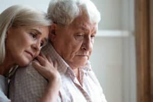 Older man being hugged by wife
