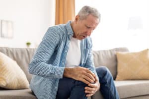 Senior man holding leg in pain