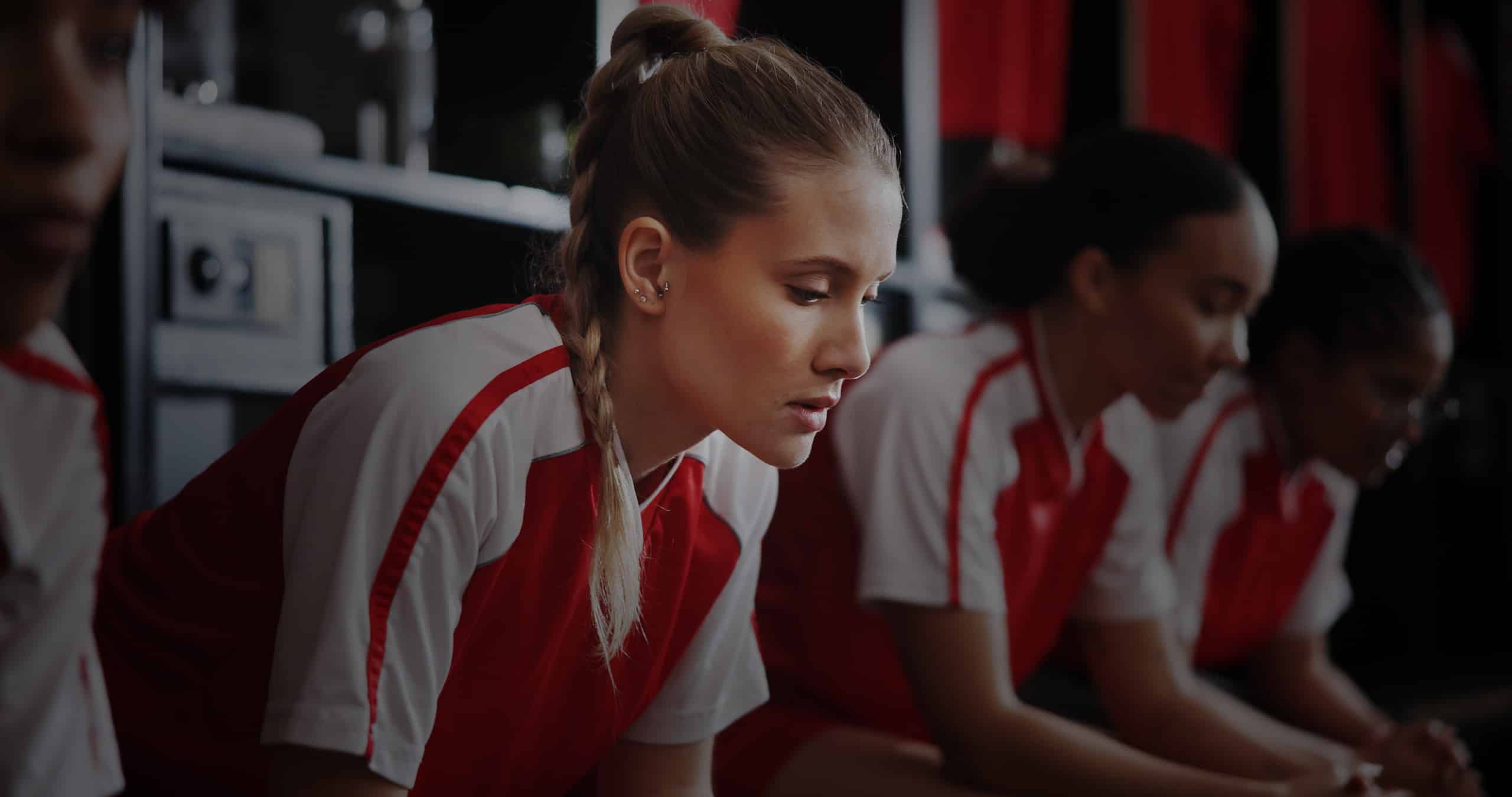 Female soccer player sits in locker room anxiously