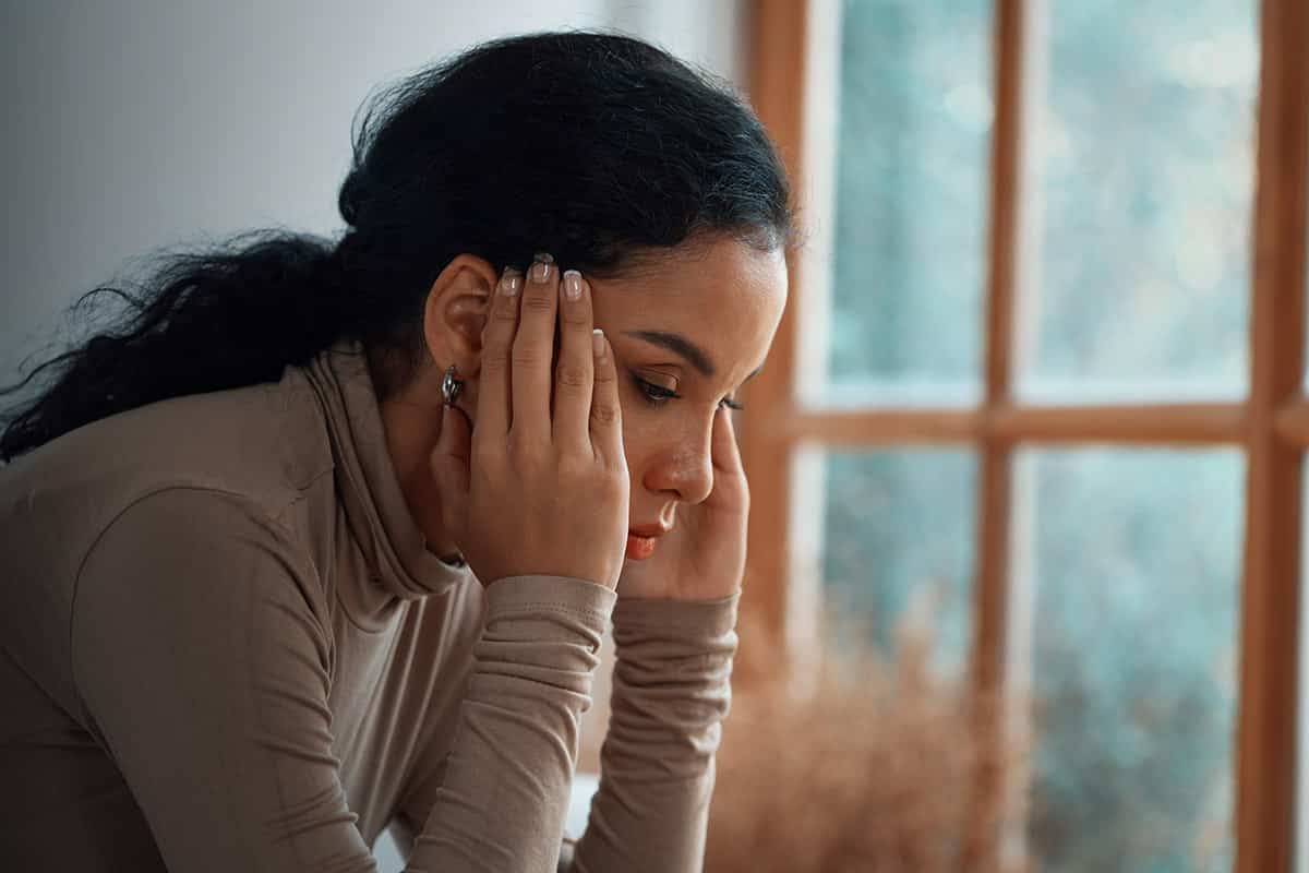Young Black woman with hands on head appearing distressed, depicting mental health struggles