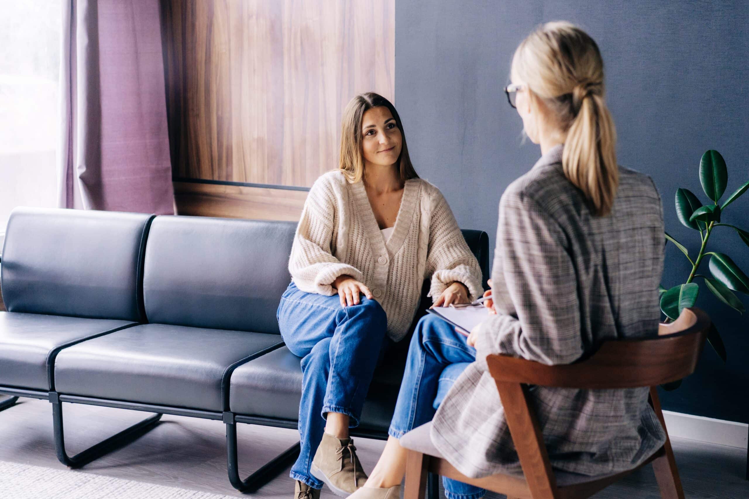 Smiling woman in consultation with professional therapist or counselor in office setting.