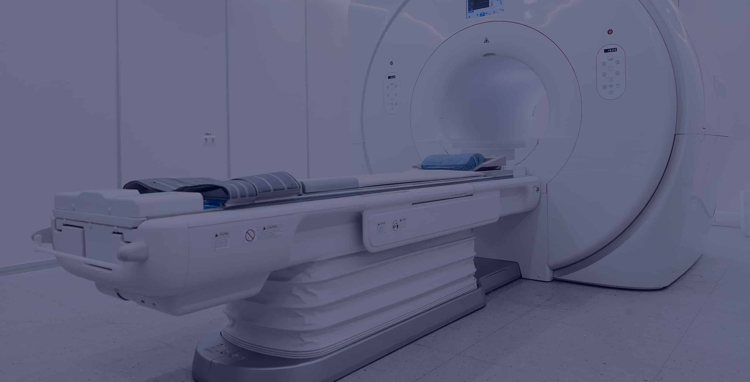 MRI (magnetic resonance imaging) machine in a white, clinical room.